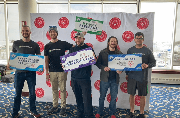 Momentum team members posing with signs for the Polar Plunge event for Special Olympics Michigan
