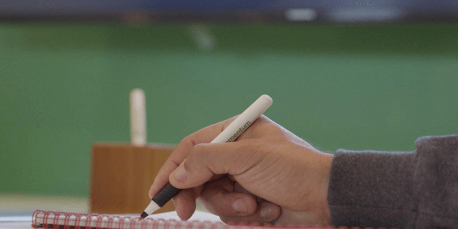 Person writing with Momentum branded pen