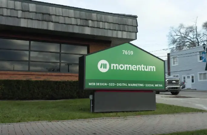 Momentum office exterior with green sign promoting web design, SEO, digital marketing, and social media services.