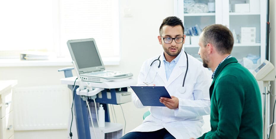 Middle-aged bearded patient having consultation with highly professional physician at modern office, they discussing diagnosis and possible treatment