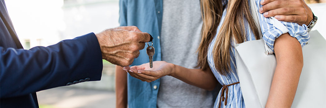 Young happy couple talking with real estate agent and buying a new house.