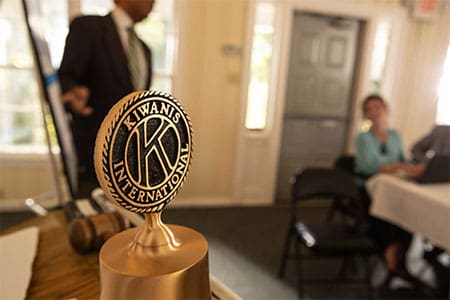 Kiwanis International emblem at a meeting with members in the background.