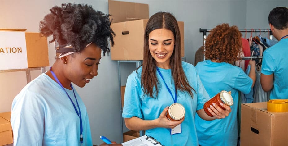 Group of people working in charitable foundation. Happy volunteer looking at donation box on a sunny day. Happy volunteer separating donations stuffs. Volunteers sort donations during food drive