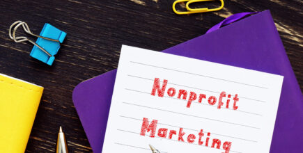 An index card with the phrase "Nonprofit marketing" sits on top of a folder on a table