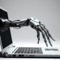 Robot hand coming out of a laptop screen to type